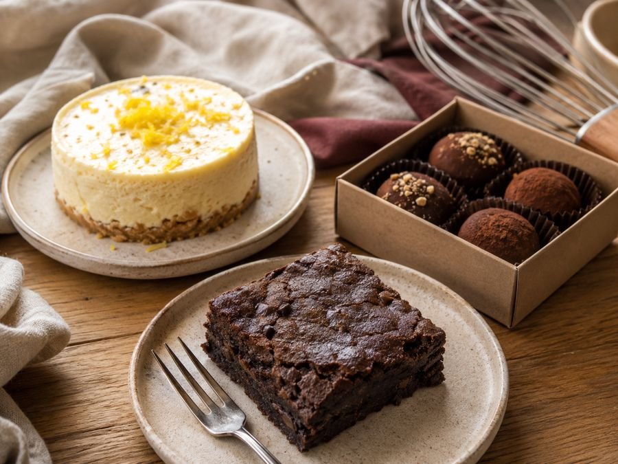 Brownie keto, cheesecake individual y caja de trufas keto sobre una mesa de madera